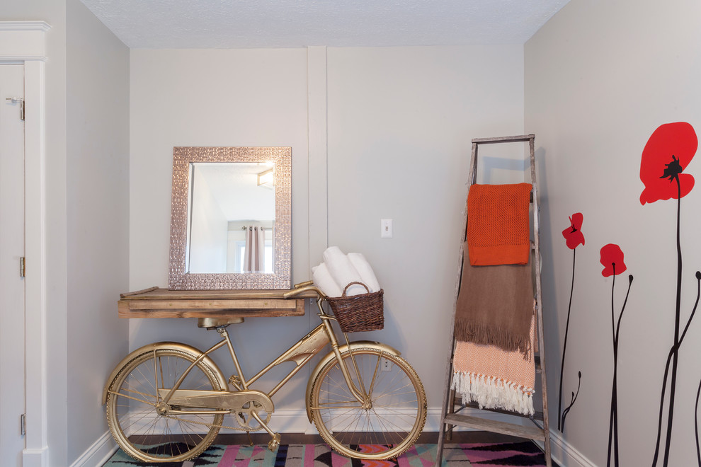 Idée de décoration pour une petite chambre d'amis bohème avec un mur gris et un sol en bois brun.