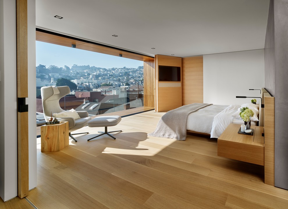 Стильный дизайн: спальня в современном стиле с белыми стенами, паркетным полом среднего тона и телевизором - последний тренд