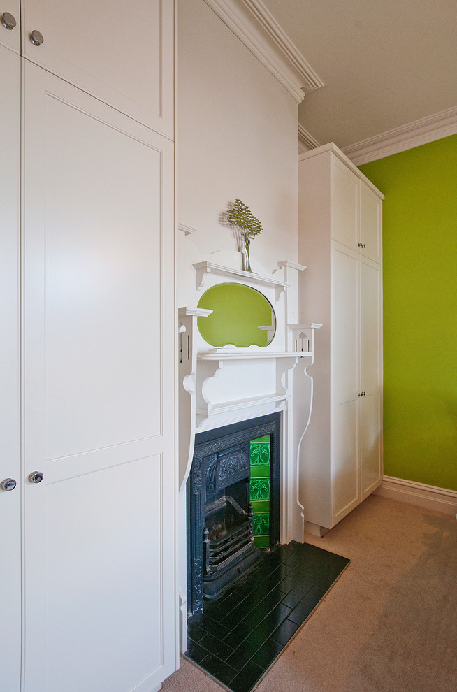 Exemple d'une grande chambre tendance avec un mur vert, une cheminée standard, un manteau de cheminée en métal et un sol beige.