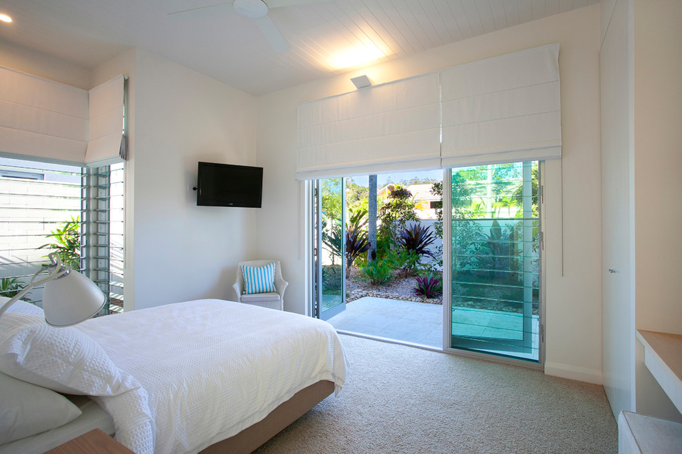 Imagen de habitación de invitados costera grande con paredes blancas, moqueta y suelo beige
