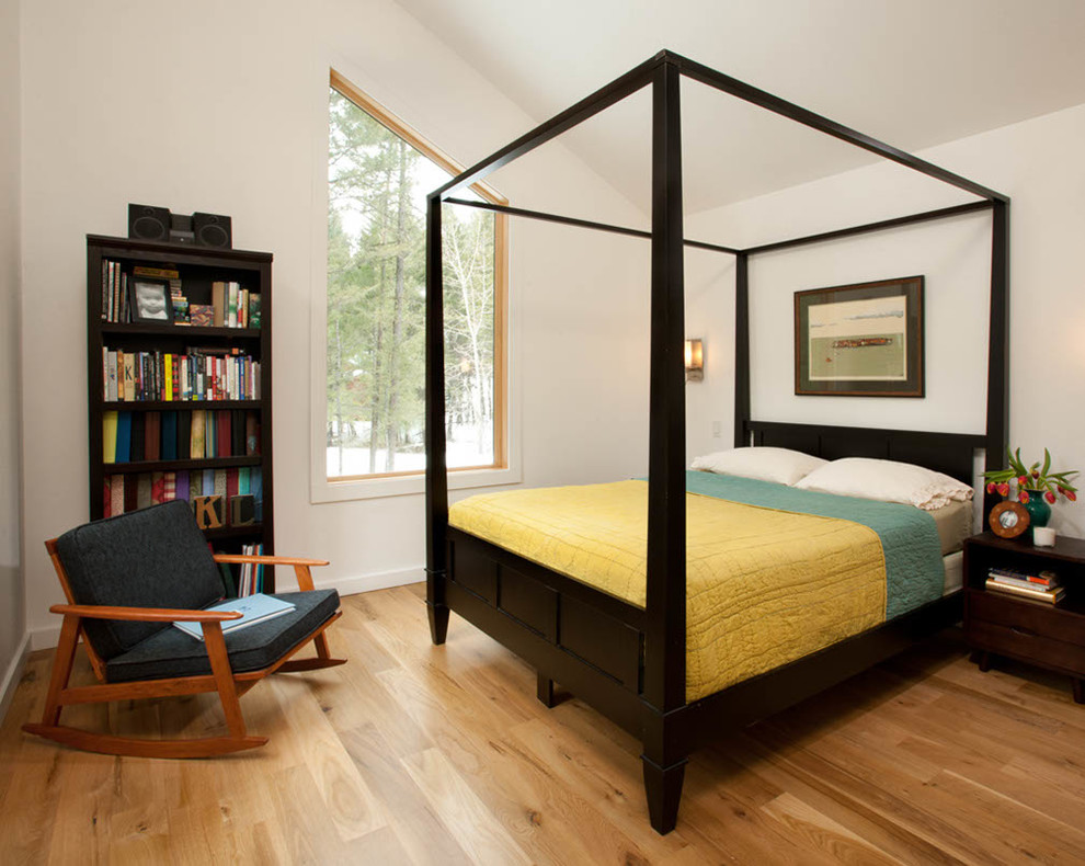 Cette photo montre une chambre d'amis tendance de taille moyenne avec un mur blanc, un sol en bois brun, aucune cheminée et un sol marron.
