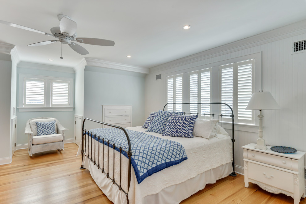 Imagen de dormitorio costero con paredes blancas y suelo de madera en tonos medios