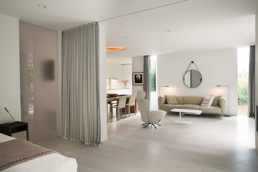 Ejemplo de dormitorio principal minimalista grande con paredes blancas, suelo de madera clara, todas las chimeneas, marco de chimenea de yeso y suelo beige