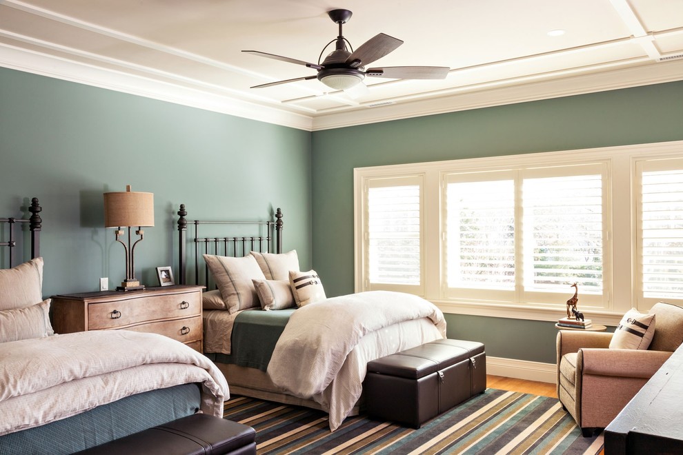 Diseño de habitación de invitados costera grande sin chimenea con paredes azules y suelo de madera en tonos medios