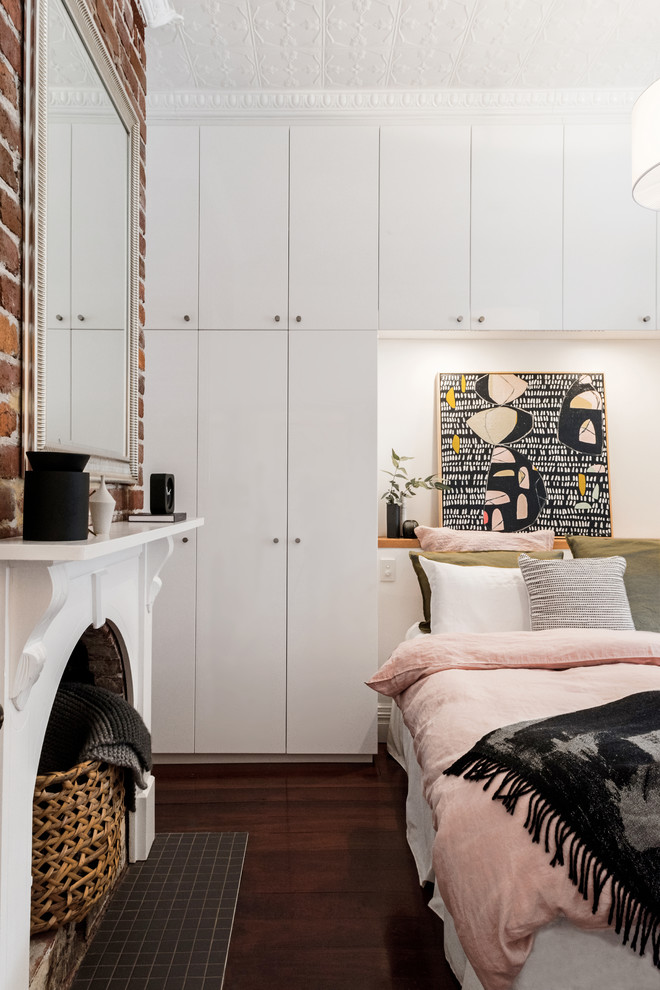 Immagine di una piccola camera matrimoniale bohémian con pareti bianche, parquet scuro, pavimento marrone e camino classico