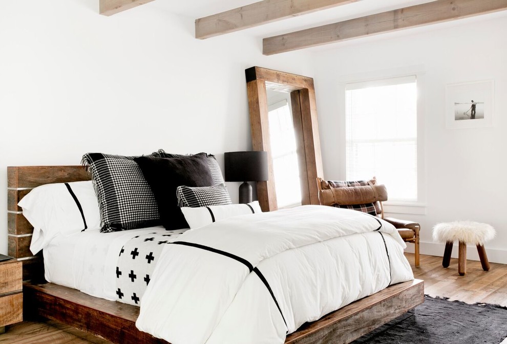 This is an example of a large rural guest bedroom in New York with white walls, brown floors and medium hardwood flooring.