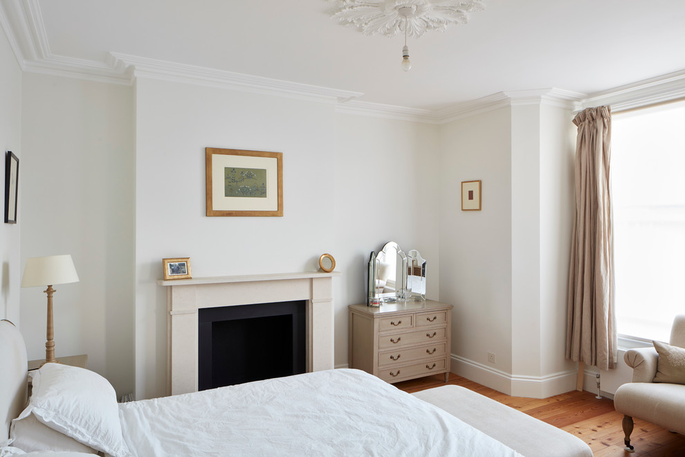 Aménagement d'une grande chambre parentale victorienne avec un mur blanc, parquet clair, une cheminée standard, un manteau de cheminée en pierre et un sol marron.