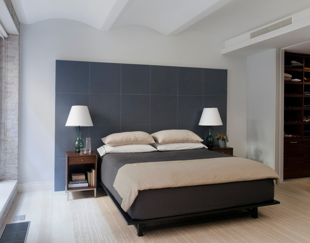Modernes Schlafzimmer ohne Kamin mit weißer Wandfarbe und hellem Holzboden in New York