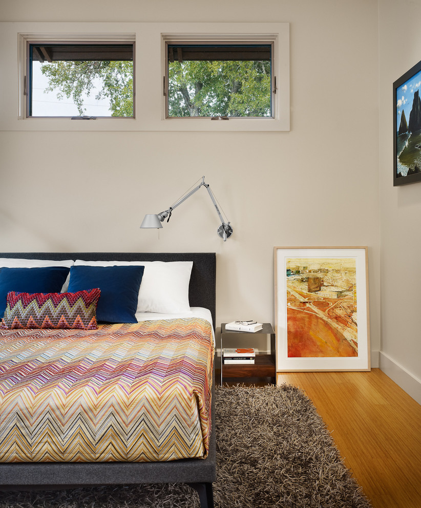 Aménagement d'une chambre parentale moderne avec un mur beige et un sol en bois brun.