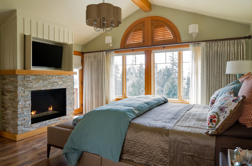 Ejemplo de dormitorio principal ecléctico de tamaño medio con paredes azules, suelo de madera en tonos medios, todas las chimeneas y marco de chimenea de piedra