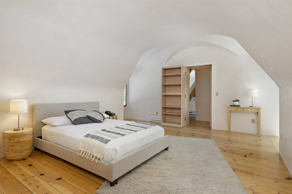 Modelo de dormitorio principal de estilo americano de tamaño medio sin chimenea con paredes beige, suelo de madera clara y suelo beige