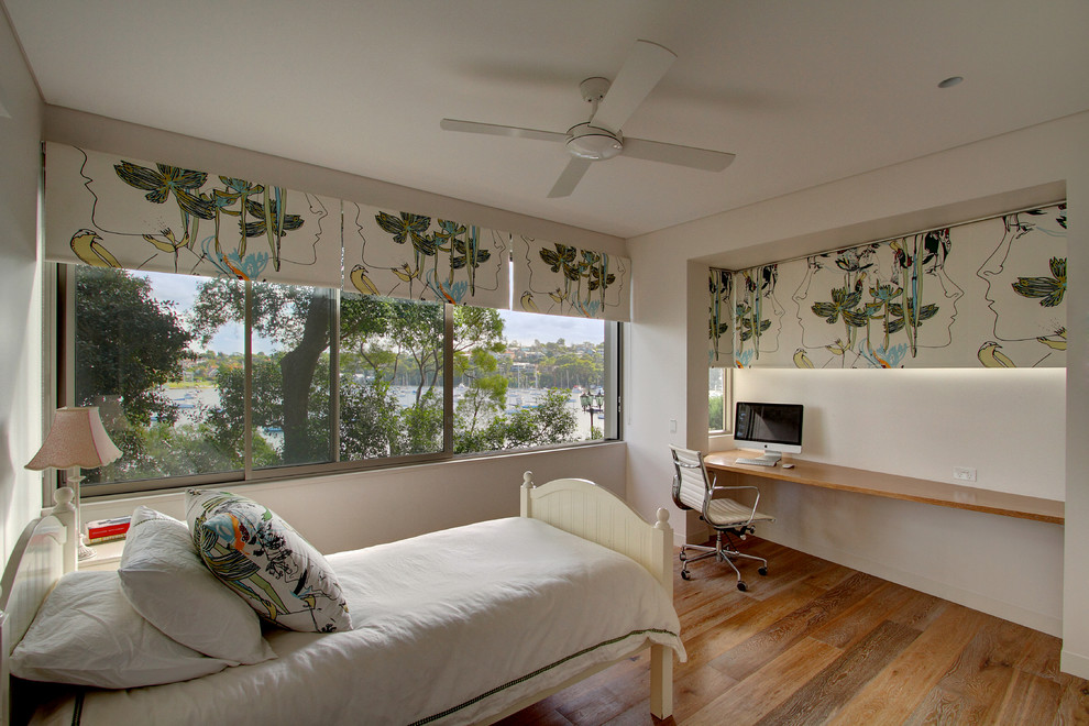 Ejemplo de habitación de invitados actual de tamaño medio con paredes blancas y suelo de madera en tonos medios