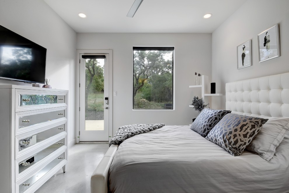 Cette image montre une chambre d'amis design de taille moyenne avec un mur blanc, sol en béton ciré et un sol gris.