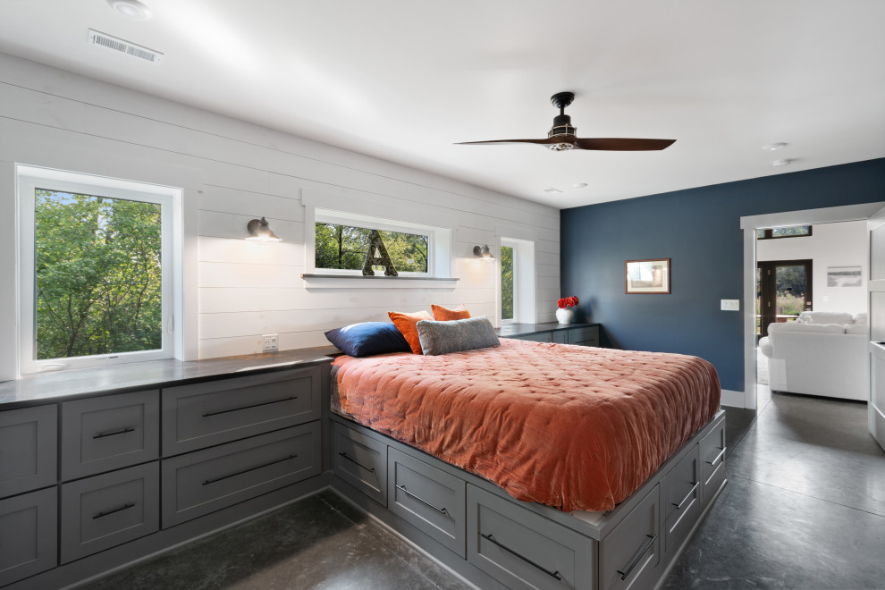 Пример оригинального дизайна: большая хозяйская спальня в стиле модернизм с синими стенами, бетонным полом, коричневым полом и стенами из вагонки