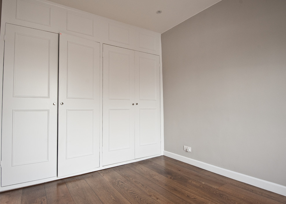 Foto di una camera degli ospiti design di medie dimensioni con pareti grigie, pavimento in legno massello medio e nessun camino