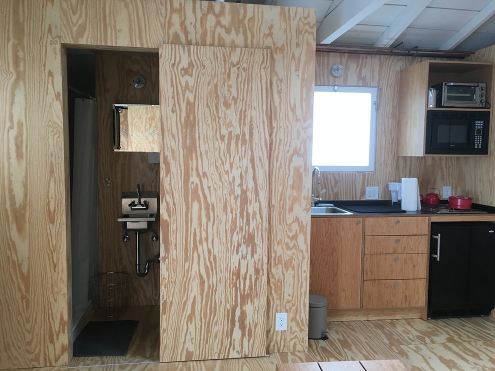 Bild på ett litet funkis gästrum, med bruna väggar, plywoodgolv och brunt golv