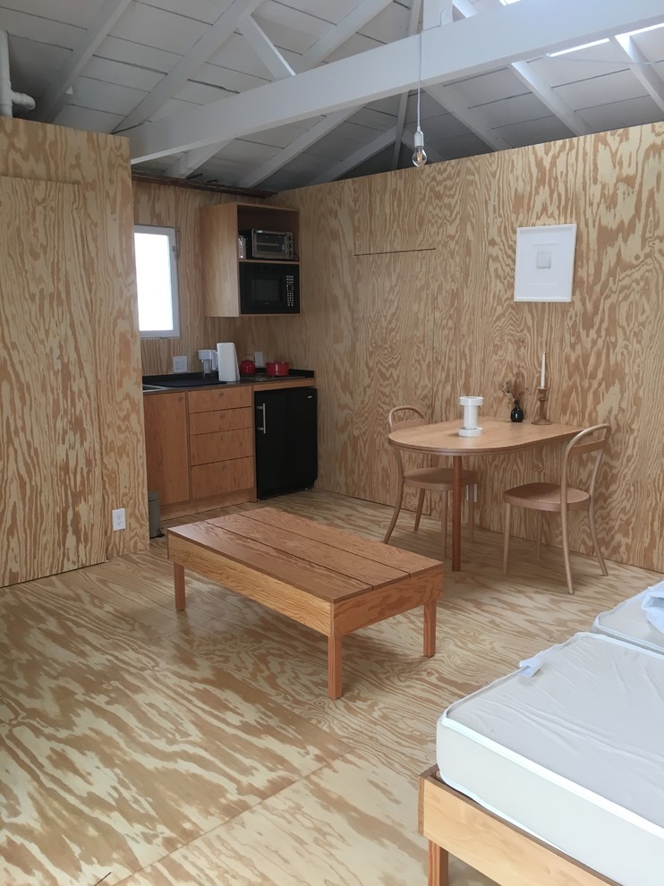 Foto på ett litet funkis gästrum, med bruna väggar, plywoodgolv och brunt golv