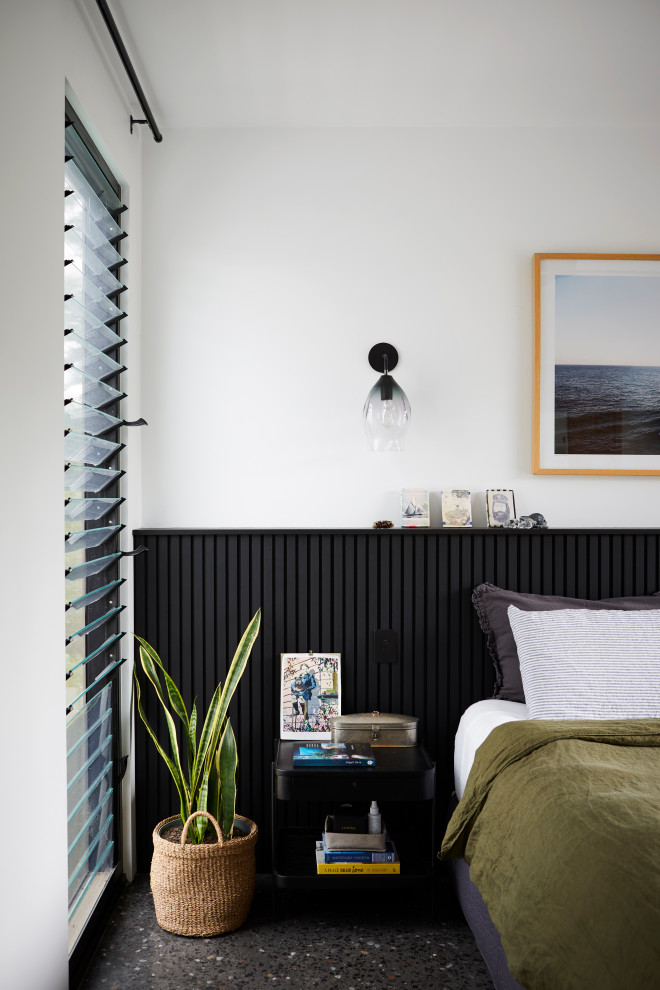 Идея дизайна: хозяйская спальня среднего размера в современном стиле с белыми стенами, бетонным полом, черным полом и панелями на стенах