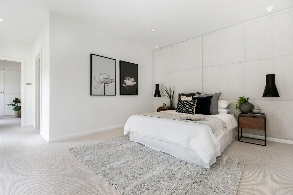 Modern inredning av ett sovrum, med vita väggar, heltäckningsmatta och grått golv