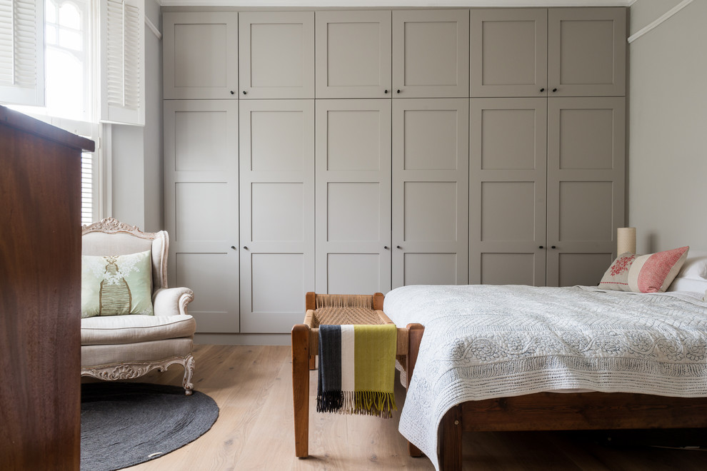 ロンドンにある広いトランジショナルスタイルのおしゃれな主寝室 (グレーの壁、淡色無垢フローリング、グレーとクリーム色)