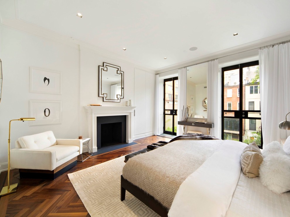 This is an example of a classic bedroom in New York with white walls, dark hardwood flooring and a standard fireplace.