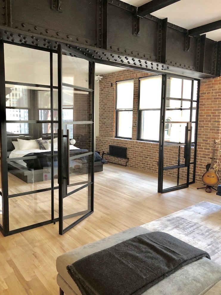 Mittelgroßes Industrial Schlafzimmer im Loft-Style mit bunten Wänden, hellem Holzboden und beigem Boden in New York