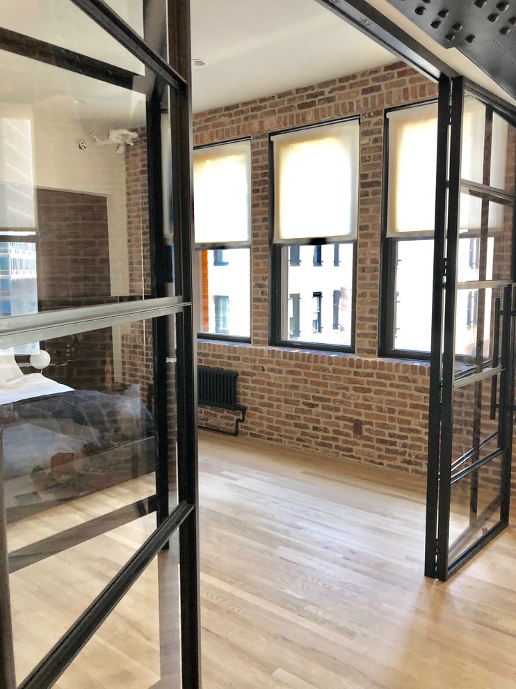 Mittelgroßes Industrial Schlafzimmer im Loft-Style mit bunten Wänden, hellem Holzboden und beigem Boden in New York