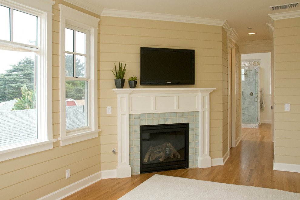 Arts and crafts master medium tone wood floor bedroom photo in San Diego with yellow walls, a corner fireplace and a tile fireplace