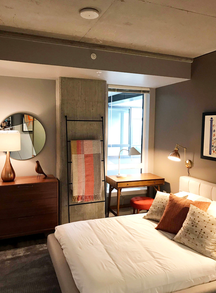 Modelo de dormitorio principal vintage pequeño sin chimenea con paredes grises, suelo laminado y suelo marrón