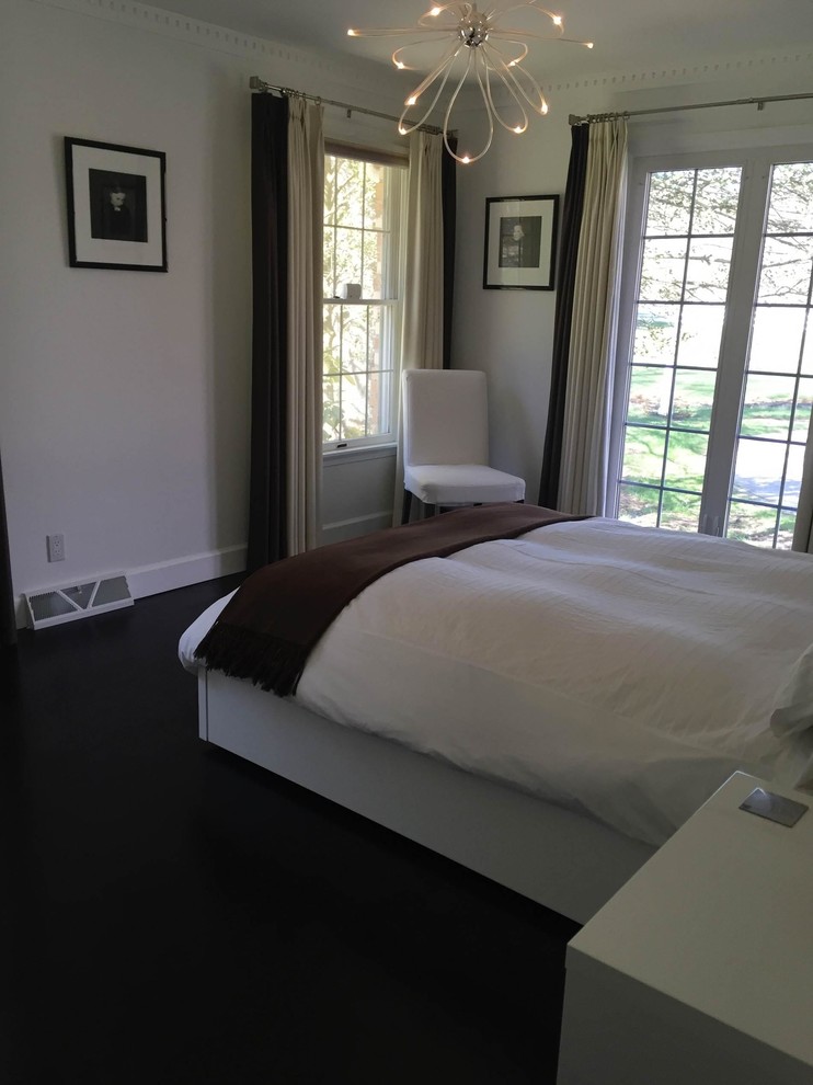 Modelo de dormitorio principal actual de tamaño medio con paredes blancas, suelo de madera oscura y suelo negro