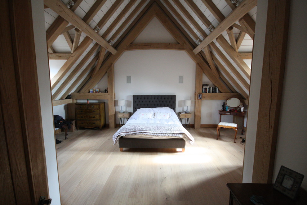 На фото: хозяйская спальня среднего размера на мансарде в стиле фьюжн с белыми стенами и светлым паркетным полом с