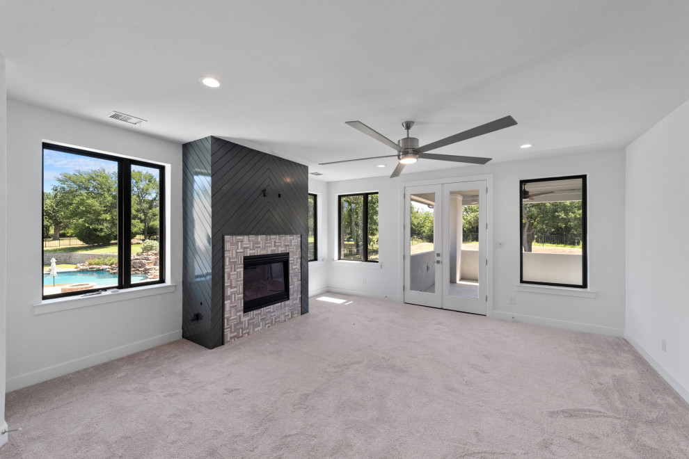 Großes Modernes Hauptschlafzimmer mit weißer Wandfarbe, Teppichboden, Kamin, gefliester Kaminumrandung, grauem Boden und Holzdielenwänden in Dallas