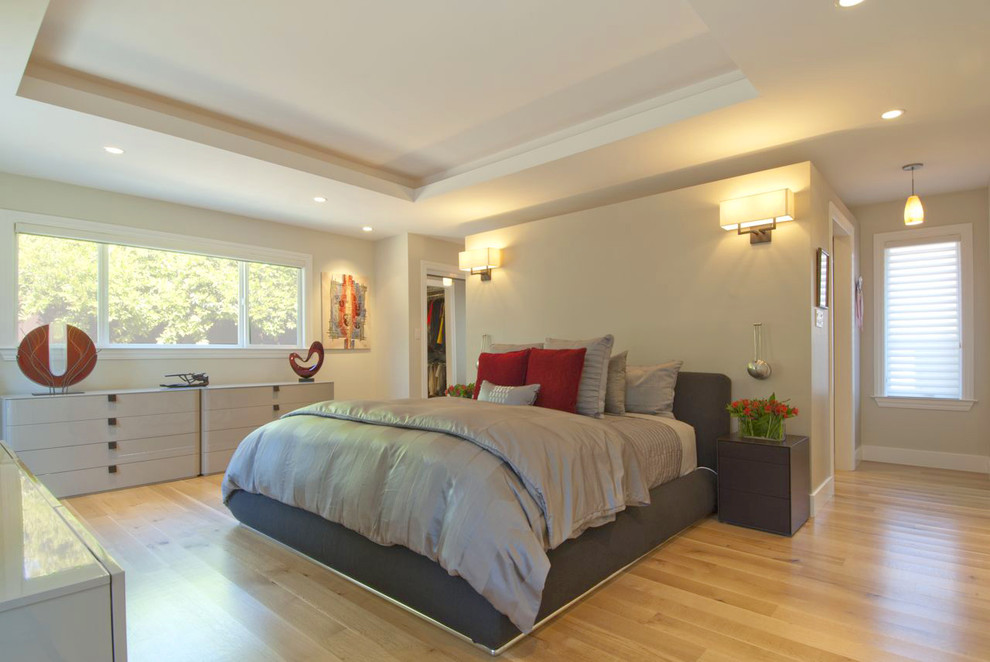 Modern inredning av ett sovrum, med beige väggar och mellanmörkt trägolv