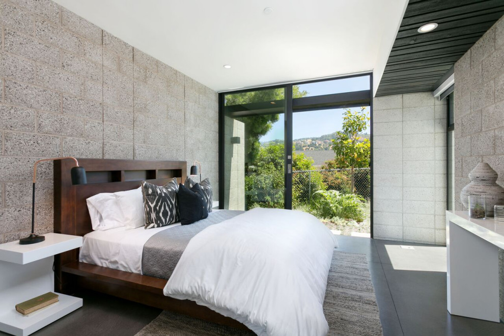 Réalisation d'une chambre d'amis design de taille moyenne avec un mur gris, sol en béton ciré, un sol gris et un mur en parement de brique.