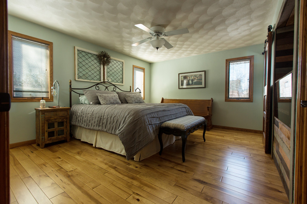 Imagen de dormitorio principal tradicional renovado de tamaño medio sin chimenea con paredes verdes, suelo de madera en tonos medios y suelo marrón