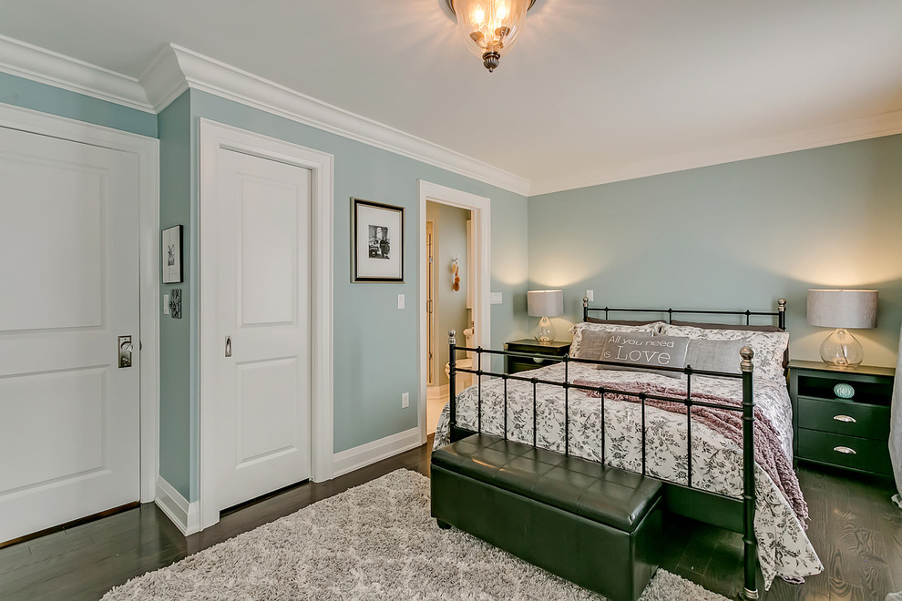Modelo de dormitorio principal clásico renovado pequeño sin chimenea con paredes verdes, suelo de madera oscura y suelo marrón