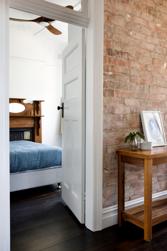 Идея дизайна: гостевая спальня (комната для гостей) в современном стиле с белыми стенами, деревянным полом, стандартным камином, фасадом камина из дерева и черным полом