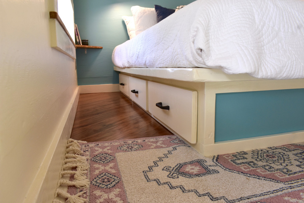 Foto de dormitorio tipo loft costero pequeño con paredes azules, suelo laminado y suelo marrón