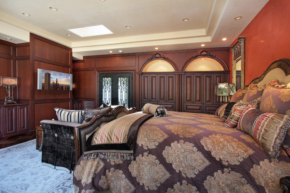 Modelo de dormitorio principal clásico grande sin chimenea con parades naranjas y suelo de madera en tonos medios