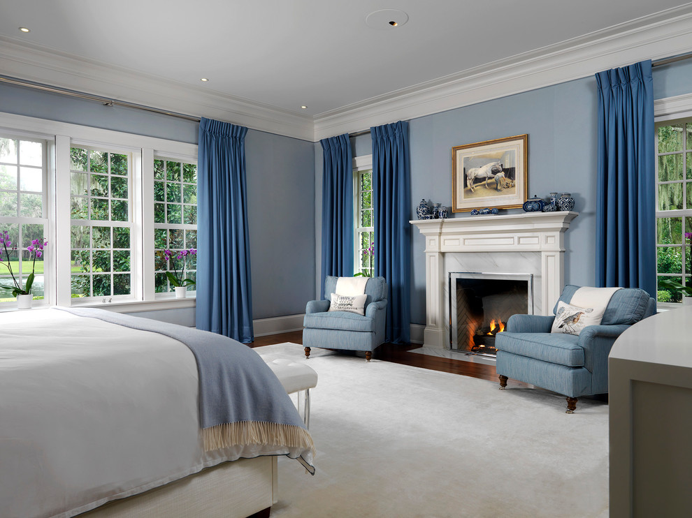 Пример оригинального дизайна: спальня в классическом стиле с синими стенами, темным паркетным полом, стандартным камином, коричневым полом и синими шторами