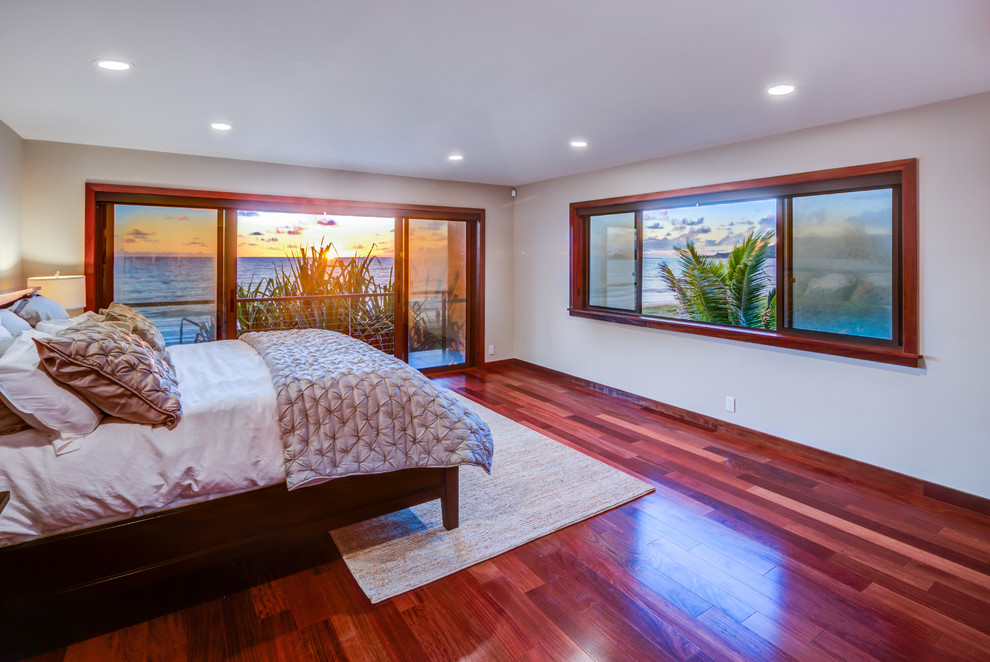 Bild på ett stort tropiskt sovrum, med vita väggar och mellanmörkt trägolv
