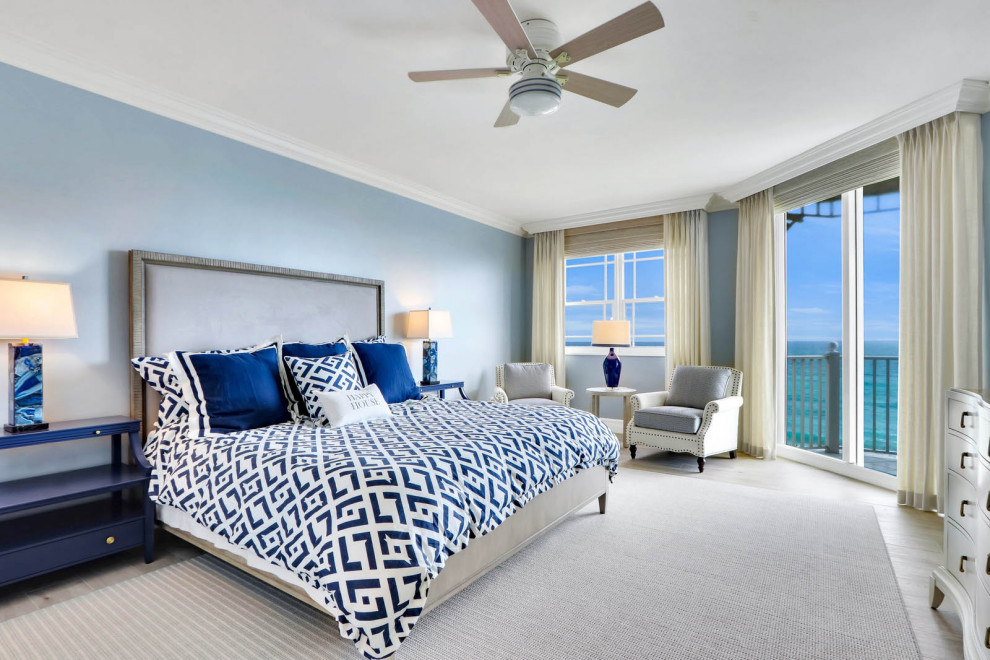 他の地域にある広いビーチスタイルのおしゃれな主寝室 (青い壁、磁器タイルの床、ベージュの床)