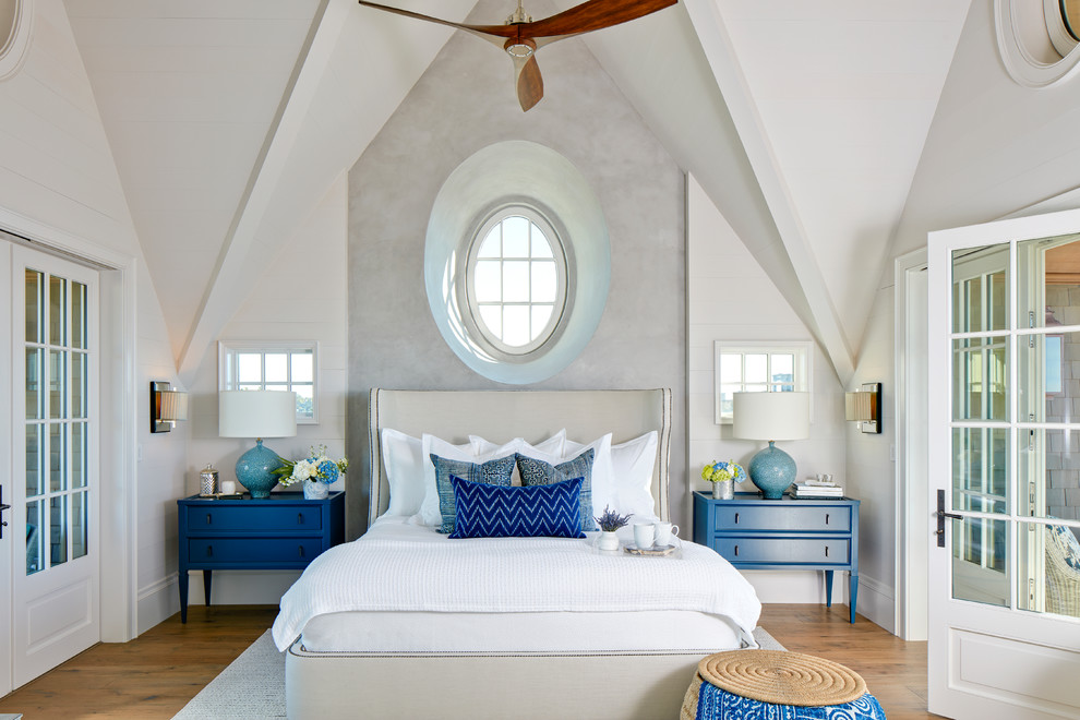 Diseño de dormitorio principal costero de tamaño medio sin chimenea con paredes blancas y suelo de madera en tonos medios