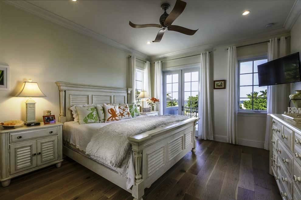Modelo de dormitorio principal exótico grande con paredes blancas y suelo de madera oscura