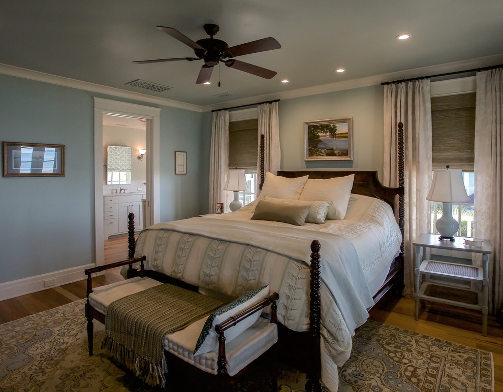 Coastal master bedroom in Charleston with green walls and light hardwood flooring.