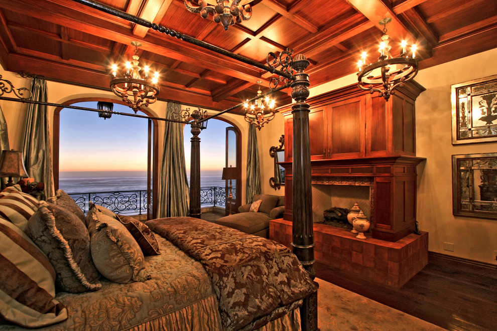 Exemple d'une chambre parentale méditerranéenne de taille moyenne avec un mur beige, parquet foncé, une cheminée standard, un manteau de cheminée en bois et un sol marron.