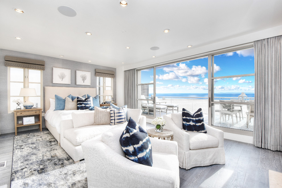 This is an example of a large nautical master bedroom in Orange County with white walls, light hardwood flooring, grey floors, a standard fireplace and a stone fireplace surround.
