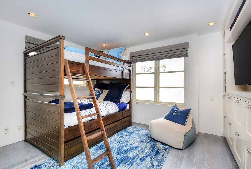 Modelo de habitación de invitados costera de tamaño medio sin chimenea con paredes blancas, suelo de madera clara y suelo gris