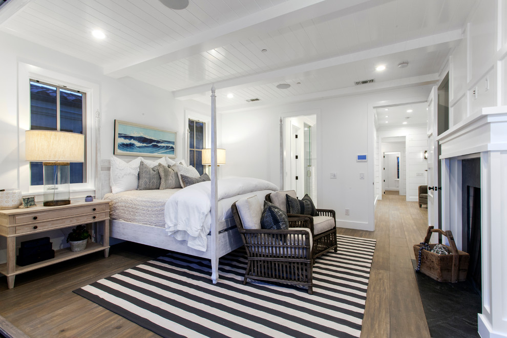 Inspiration for a large coastal master medium tone wood floor bedroom remodel in Orange County with white walls, a standard fireplace and a stone fireplace