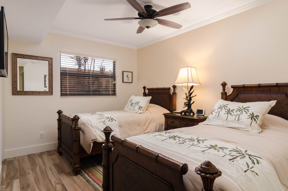 Modelo de habitación de invitados costera pequeña sin chimenea con paredes beige, suelo laminado y suelo beige